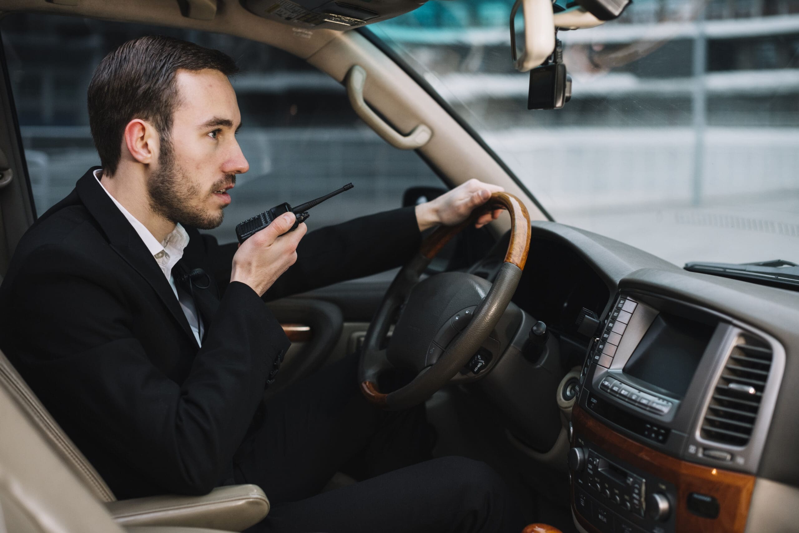 Sicherheitsmitarbeiter beim Revierwachdienst in Berlin spricht über Funkgerät während einer Kontrollfahrt im Dienstfahrzeug.